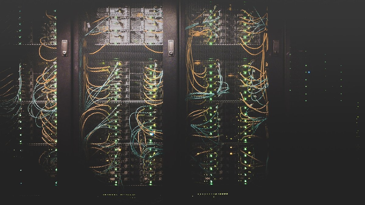 Rows of aging server cabinets tangled with patch cables in a dim data centre