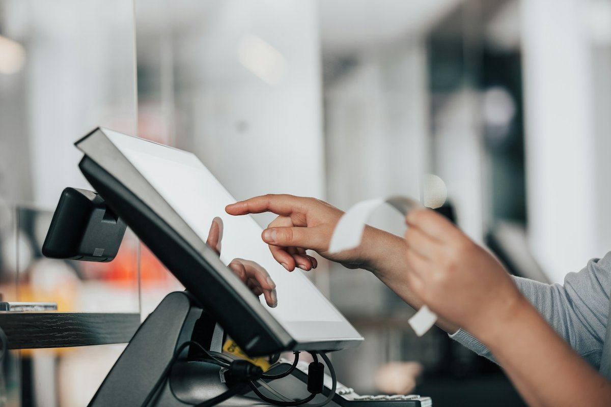 Cashier operating a point of sale terminal and tearing off a receipt