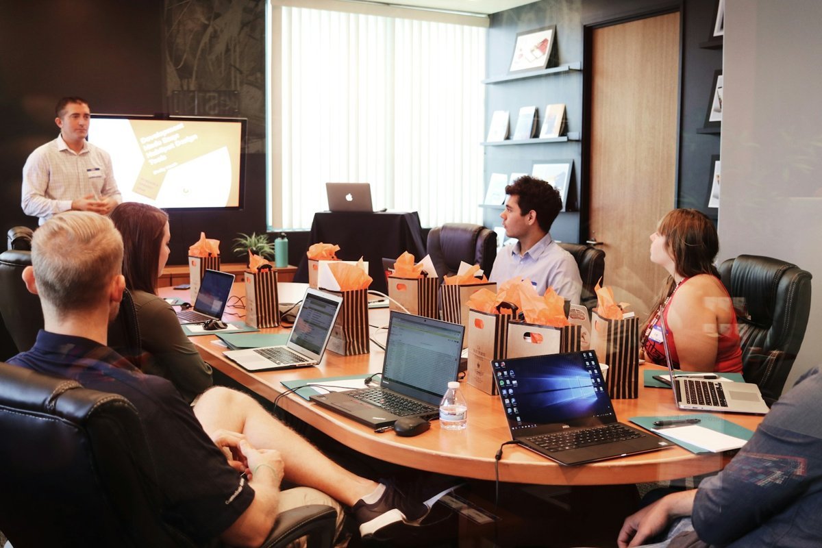 Team gathered around a boardroom table with laptops during a platform workshop