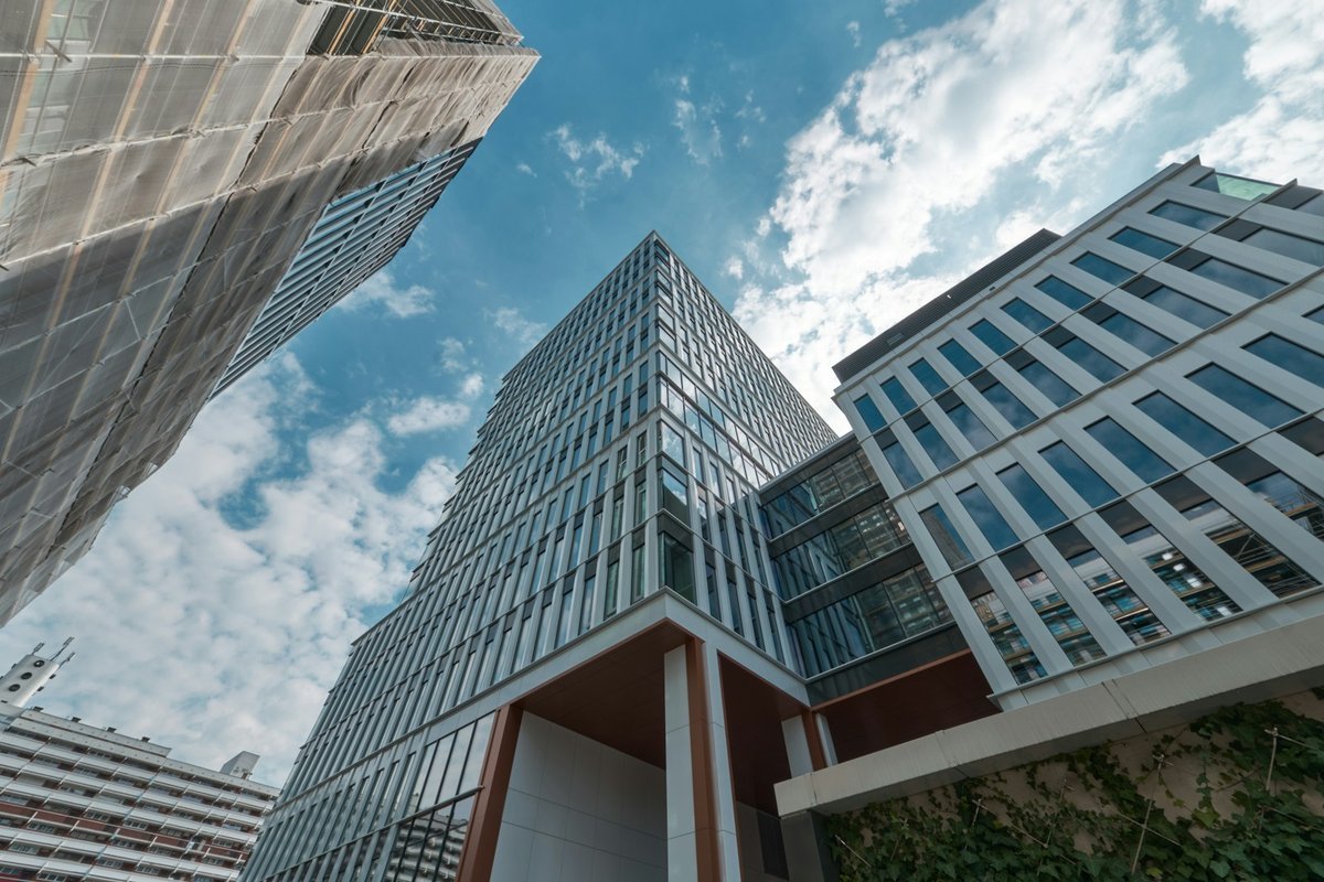 Separate corporate office towers seen from street level against a bright sky