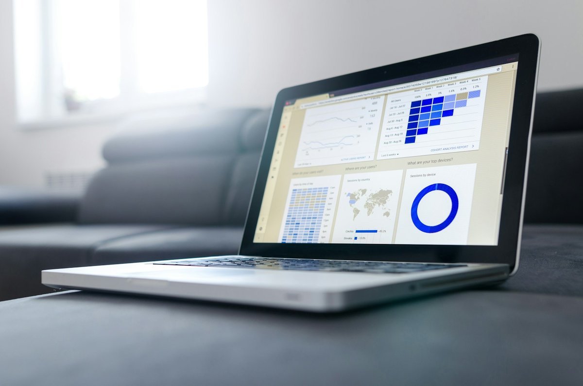 Laptop on a table showing an analytics dashboard with charts and tables