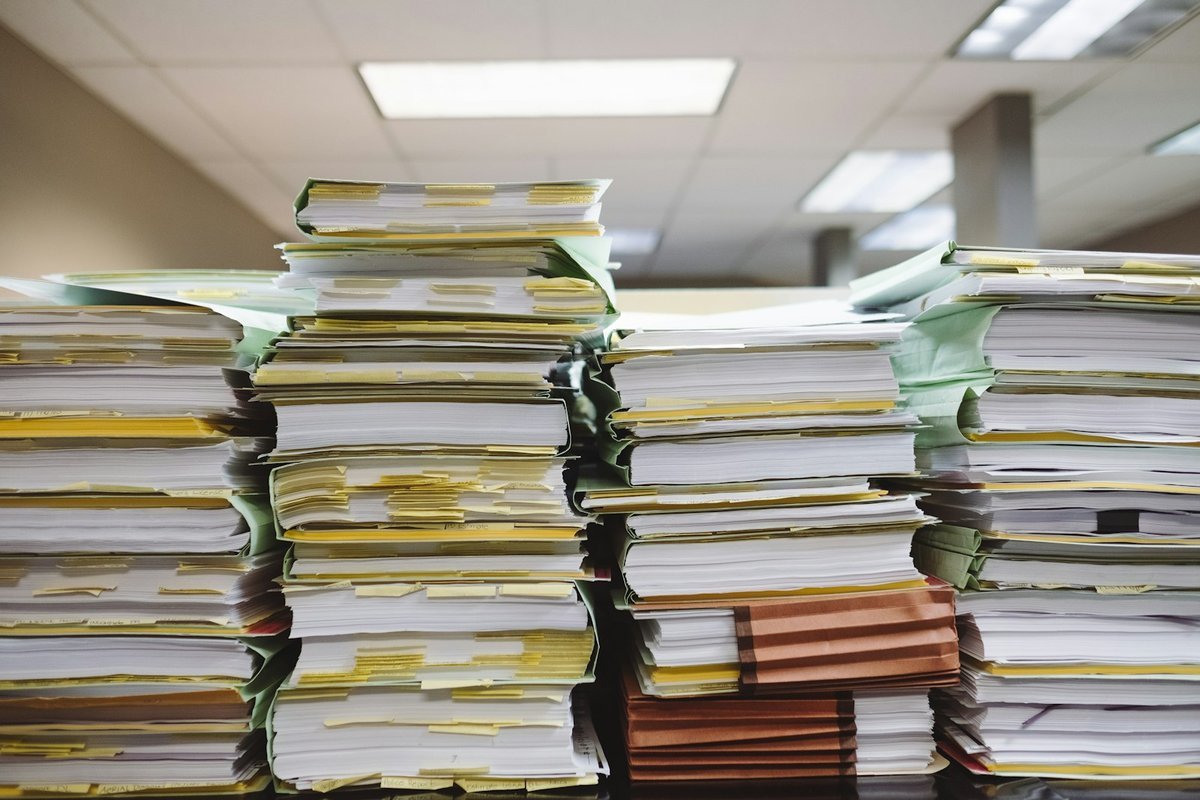 Tall stacks of paper files and folders on an office desk