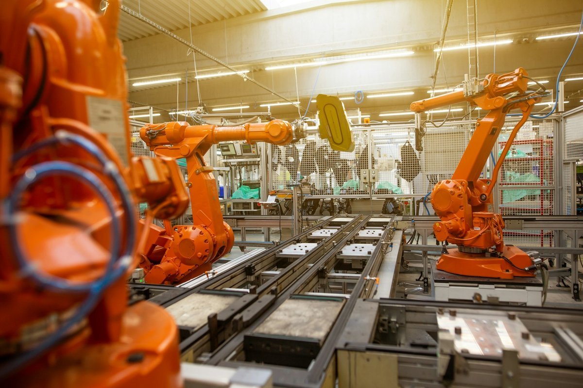 Robotic arms moving parts along an automated production line