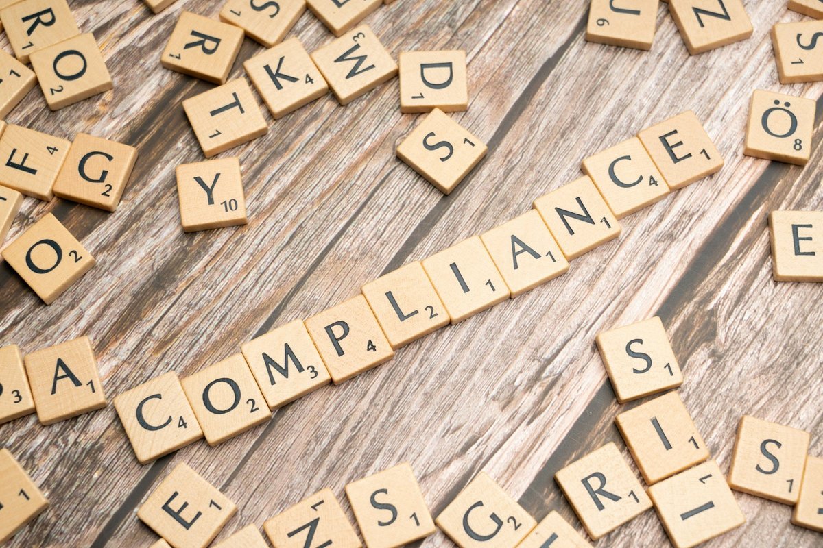 Wooden letter tiles on a table spelling out the word compliance
