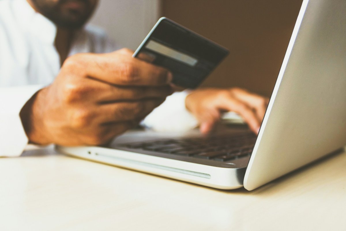 Shopper holding a bank card while ordering on a laptop