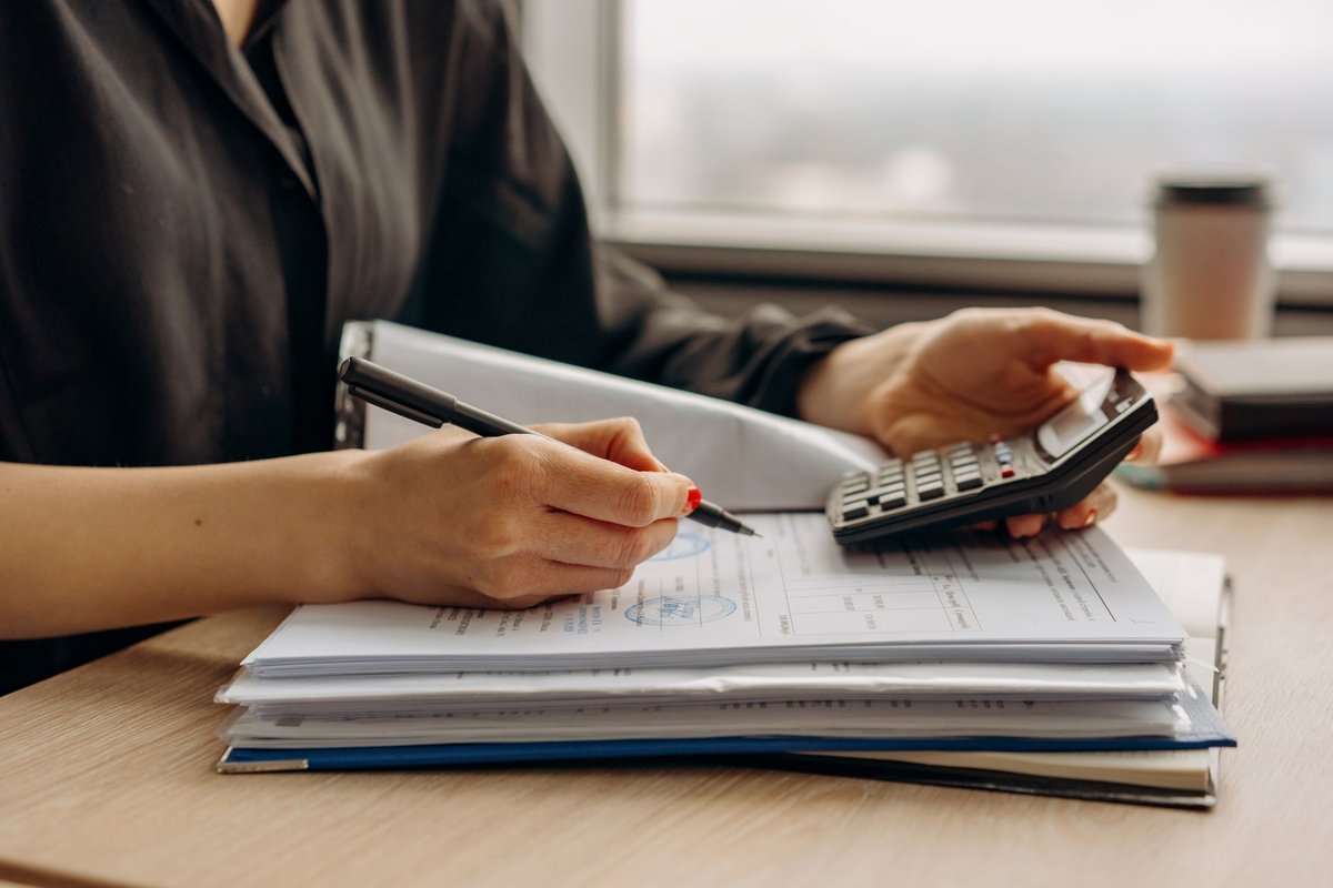 Finance officer working through invoices with a calculator