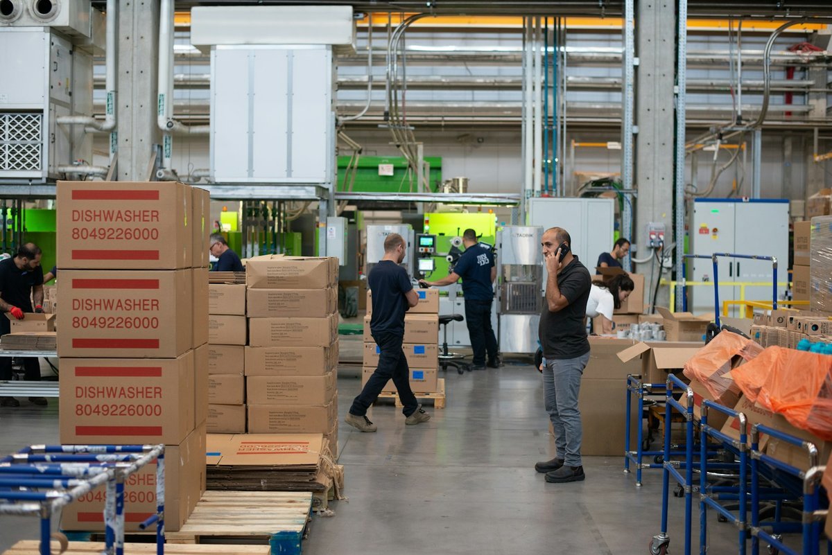 Fulfilment centre floor with stacked cartons and staff packing orders