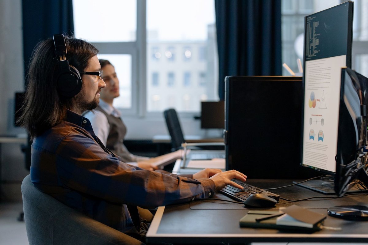 Software engineer working across two monitors in an office