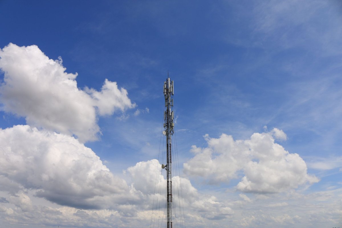 Telecom mast antenna against a bright cloudy sky