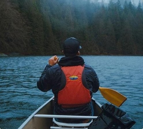 A person paddling a canoe across a calm forested lake