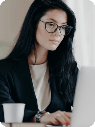 Woman with glasses working on a laptop.