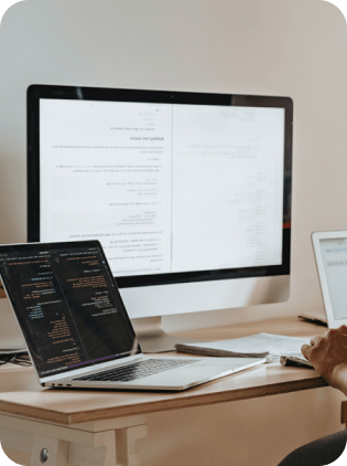 Workspace with laptop, monitor, and code displayed on screens.