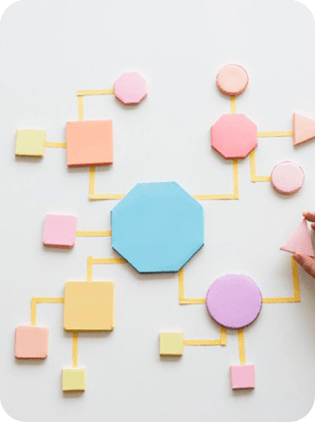 Hand arranging colorful geometric shapes in a flowchart diagram.