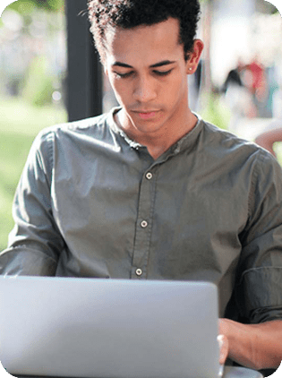 Young man working on laptop outdoors.