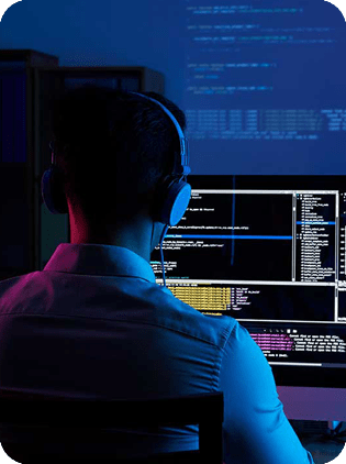 Programmer with headphones working on computer code.