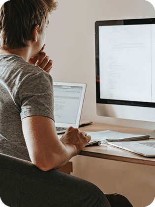 Developer working with code on computer and laptop.