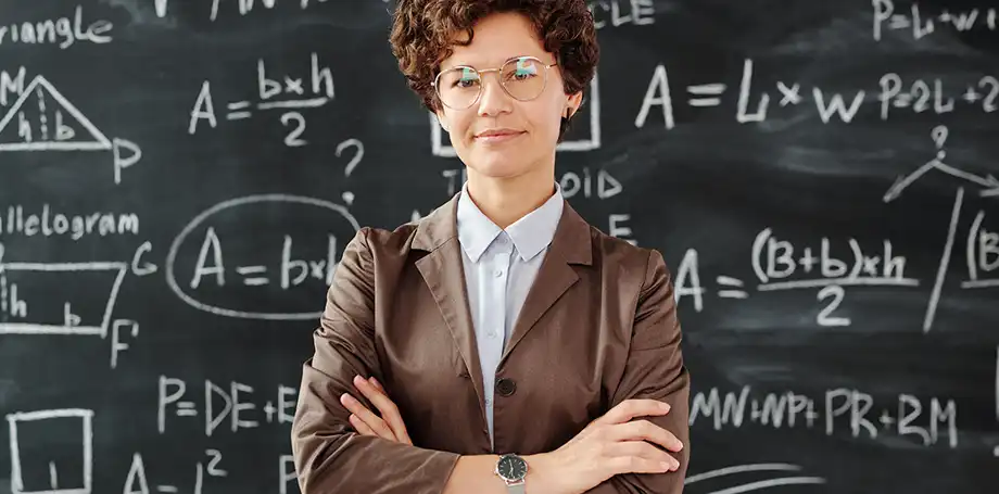 Female math teacher with equations on a blackboard.