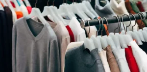 Clothing rack with various sweaters and shirts on hangers.