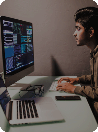Programmer focused on a computer screen displaying code.