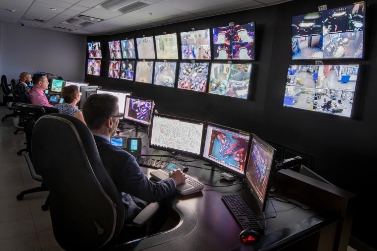 Security control room with operators viewing many surveillance monitors.