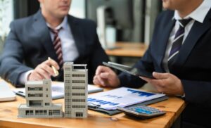 Real estate developers reviewing building models and financial charts.