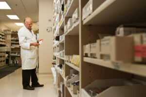 Pharmacist examining medication in a pharmacy supply room.